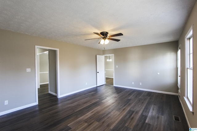 spare room with a textured ceiling, a healthy amount of sunlight, and dark wood-type flooring