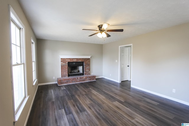 unfurnished living room with ceiling fan, dark hardwood / wood-style flooring, a textured ceiling, and a brick fireplace