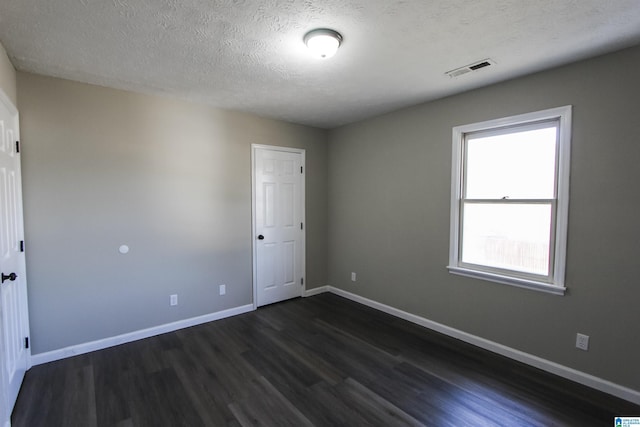 empty room with dark hardwood / wood-style flooring and a textured ceiling