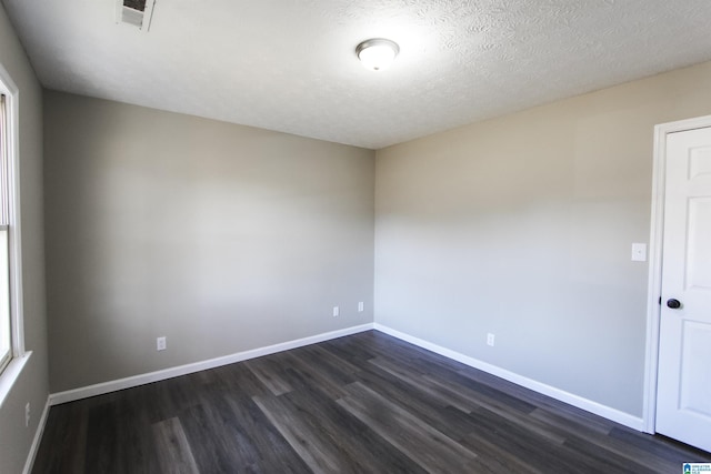 empty room with a textured ceiling and dark hardwood / wood-style floors