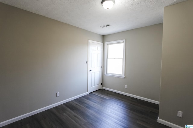 spare room with a textured ceiling and dark hardwood / wood-style floors