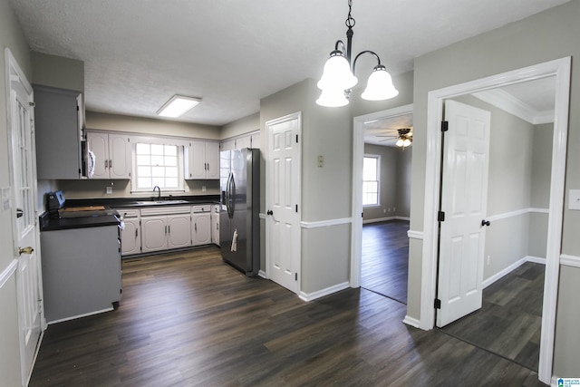 kitchen with gray cabinetry, sink, dark wood-type flooring, stainless steel appliances, and ceiling fan with notable chandelier