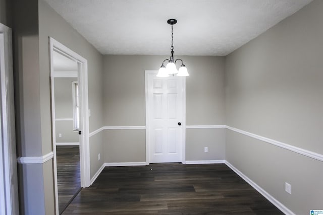 unfurnished dining area featuring a chandelier, dark wood-type flooring, and a textured ceiling