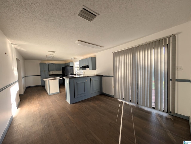 kitchen featuring gray cabinets, dark hardwood / wood-style flooring, a textured ceiling, and a wealth of natural light