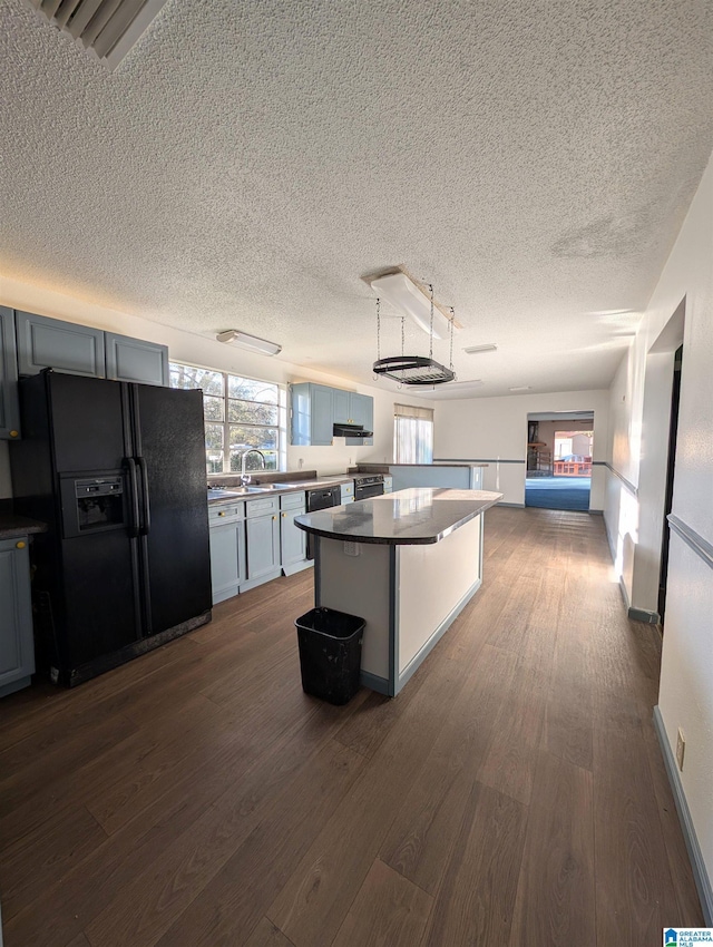 kitchen with black refrigerator with ice dispenser, dark hardwood / wood-style floors, ventilation hood, a textured ceiling, and a kitchen island