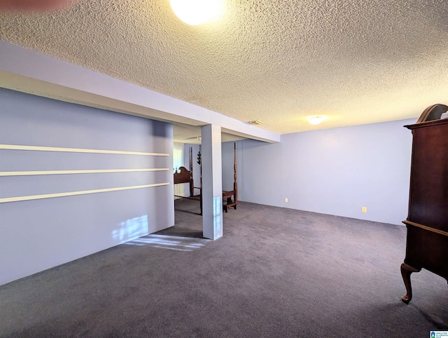 basement with dark carpet and a textured ceiling