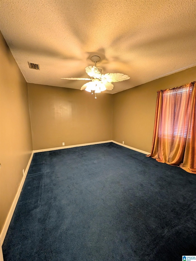 spare room featuring a textured ceiling, dark carpet, and ceiling fan