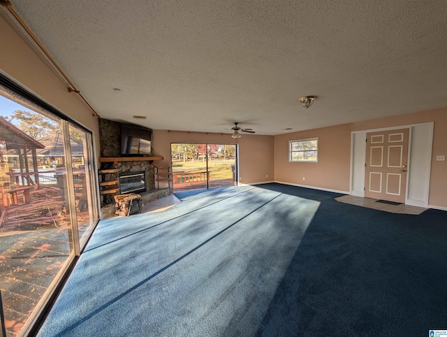 unfurnished living room with a fireplace, a textured ceiling, ceiling fan, and carpet flooring