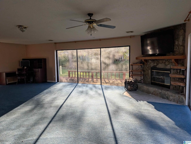 living room featuring carpet flooring, a stone fireplace, ceiling fan, and a textured ceiling