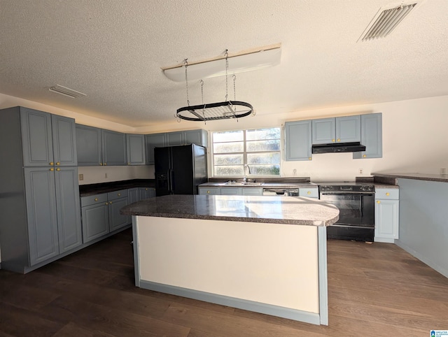 kitchen with a center island, sink, dark hardwood / wood-style floors, a textured ceiling, and black appliances