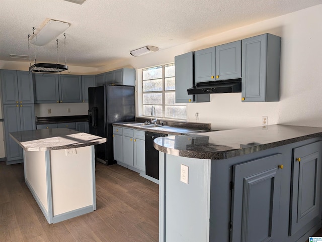 kitchen featuring hardwood / wood-style flooring, black appliances, sink, and a textured ceiling