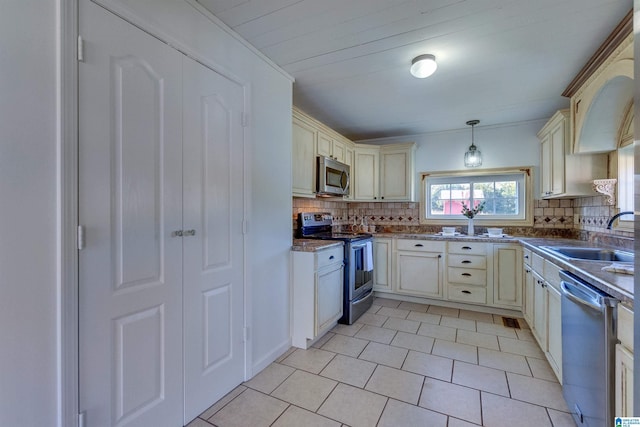 kitchen featuring pendant lighting, sink, stainless steel appliances, and cream cabinets