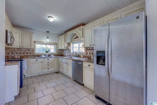 kitchen with appliances with stainless steel finishes, tasteful backsplash, hanging light fixtures, and cream cabinets