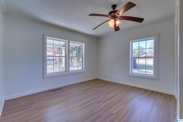 empty room with a textured ceiling, light wood-type flooring, ceiling fan, and crown molding