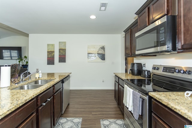 kitchen featuring appliances with stainless steel finishes, dark hardwood / wood-style flooring, light stone counters, dark brown cabinets, and sink