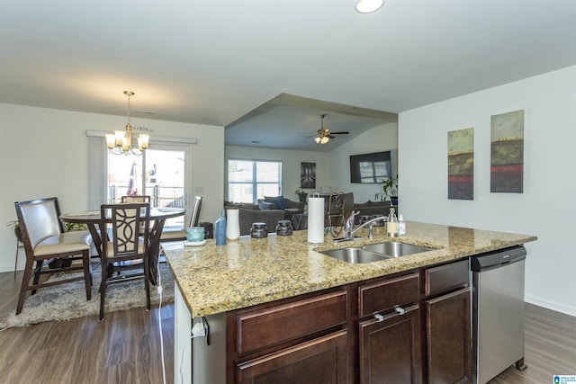 kitchen featuring dark wood-type flooring, a center island with sink, ceiling fan with notable chandelier, sink, and stainless steel dishwasher