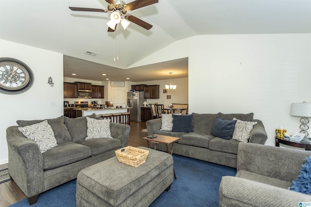 living room featuring ceiling fan with notable chandelier, dark hardwood / wood-style floors, and vaulted ceiling