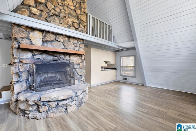 unfurnished living room featuring a fireplace, high vaulted ceiling, hardwood / wood-style floors, and beamed ceiling