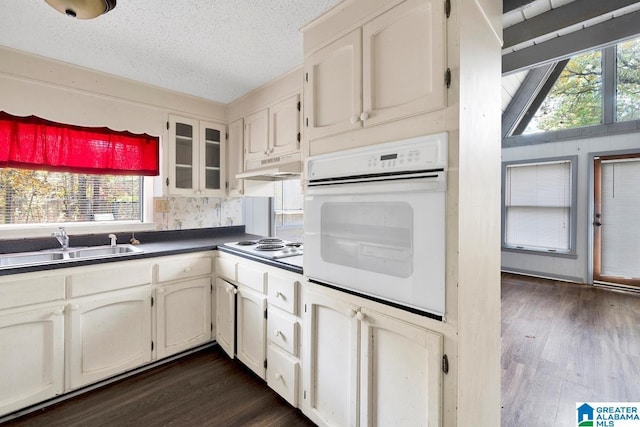 kitchen featuring white cabinets, plenty of natural light, white appliances, and dark wood-type flooring