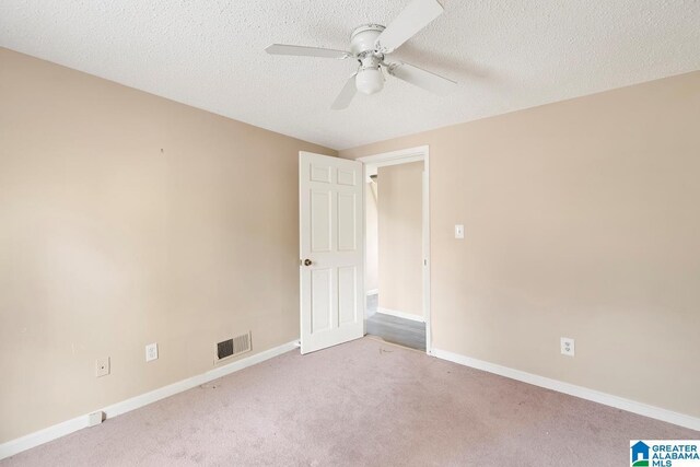 carpeted empty room with ceiling fan and a textured ceiling