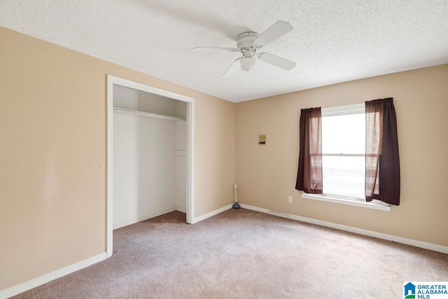 unfurnished bedroom with light carpet, a textured ceiling, a closet, and ceiling fan