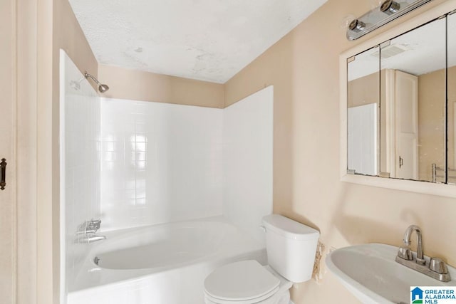 full bathroom featuring sink, tiled shower / bath, a textured ceiling, and toilet