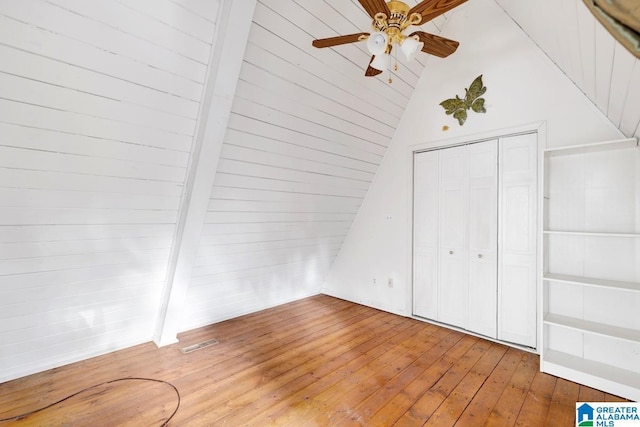 bonus room with ceiling fan, beamed ceiling, high vaulted ceiling, wood walls, and wood-type flooring