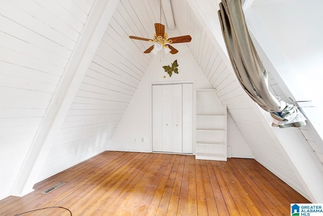 additional living space featuring wood-type flooring, high vaulted ceiling, ceiling fan, and wood walls