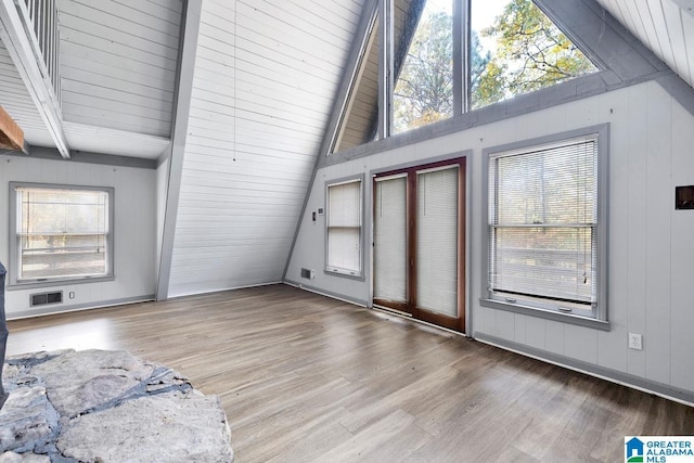 interior space with light wood-type flooring, vaulted ceiling with beams, and plenty of natural light