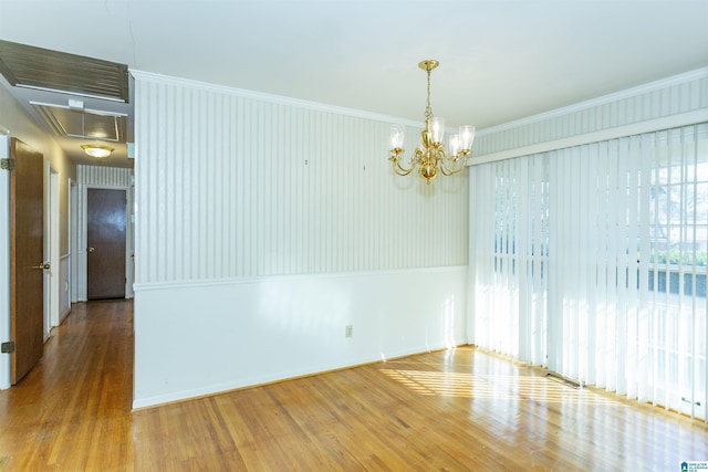 spare room with a chandelier, hardwood / wood-style floors, and crown molding