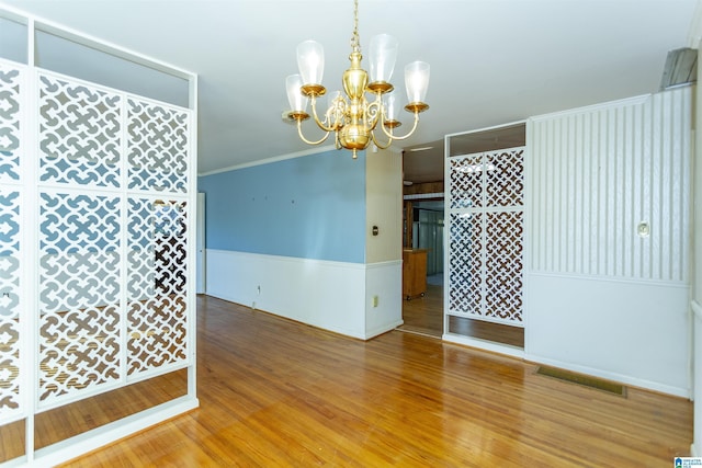 empty room with hardwood / wood-style flooring and a notable chandelier