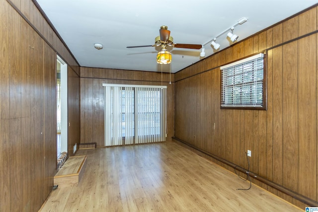 unfurnished room with ceiling fan, wood walls, light wood-type flooring, and rail lighting