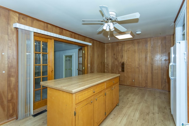 kitchen featuring light wood-type flooring, white fridge, ceiling fan, and wooden walls