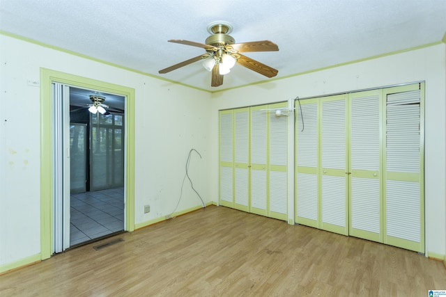 unfurnished bedroom featuring multiple closets, ceiling fan, and light wood-type flooring