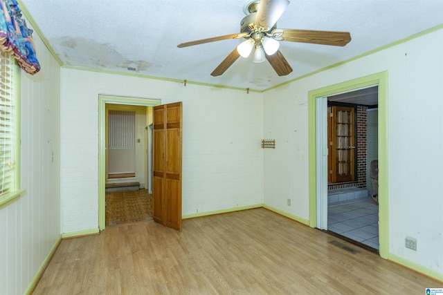 empty room with ceiling fan, ornamental molding, and light wood-type flooring