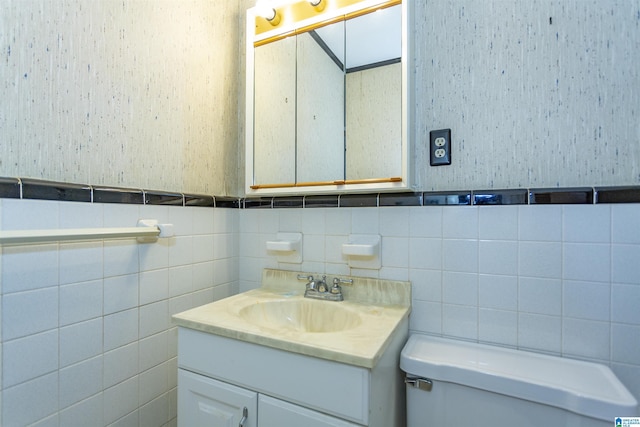 bathroom with vanity, tile walls, and toilet