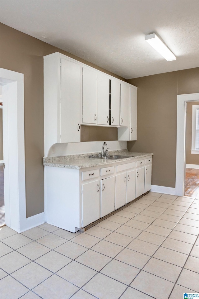 kitchen featuring white cabinets, light tile patterned floors, sink, and a textured ceiling