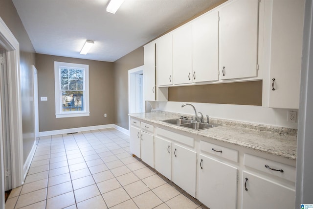 kitchen featuring white cabinets, light tile patterned floors, and sink