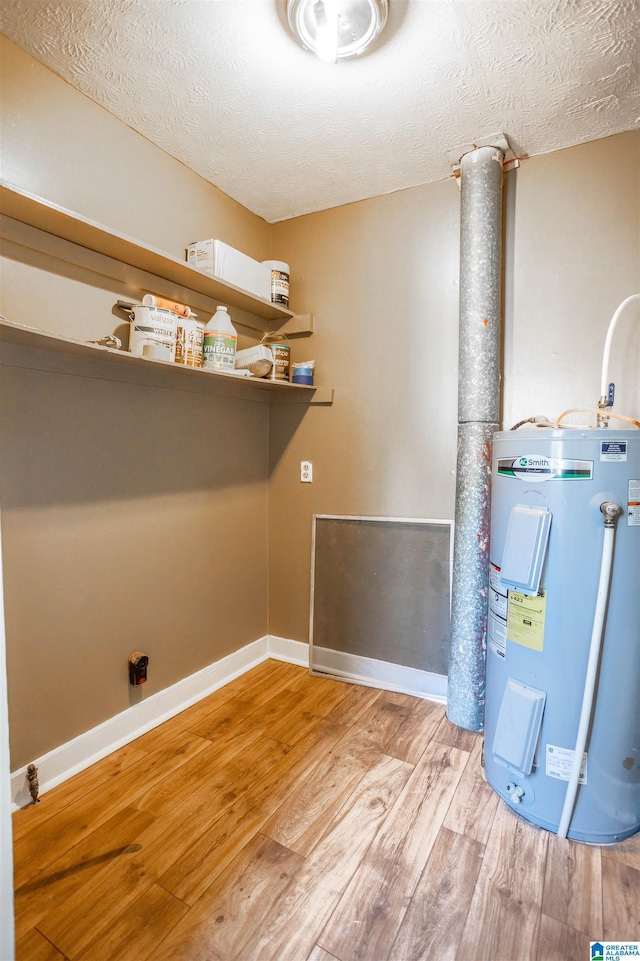 laundry area featuring a textured ceiling, light hardwood / wood-style flooring, and water heater