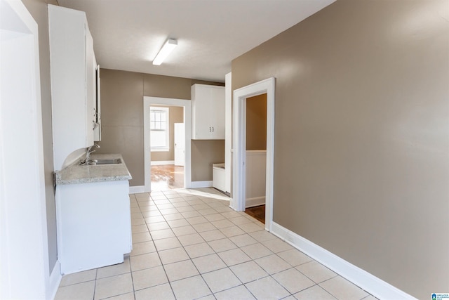 interior space featuring white cabinets, light tile patterned flooring, and sink