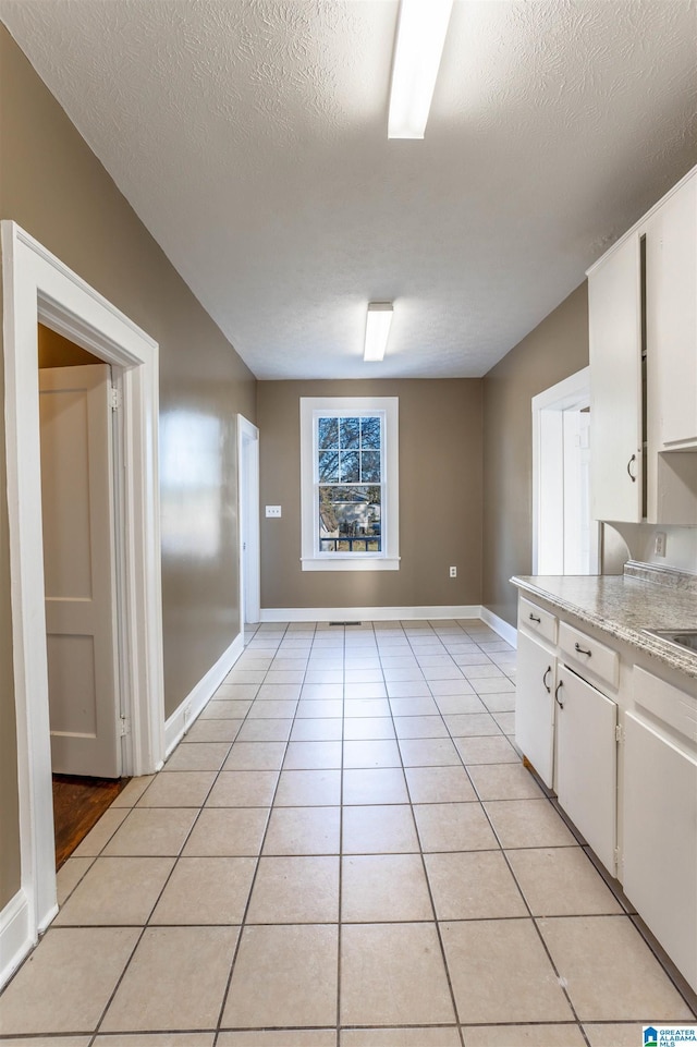 kitchen featuring white cabinets, a textured ceiling, sink, and light tile patterned flooring