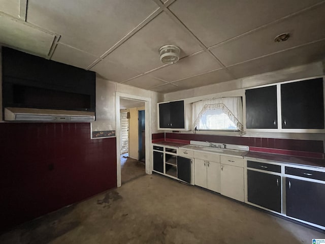 kitchen with white cabinetry, concrete flooring, and a sink