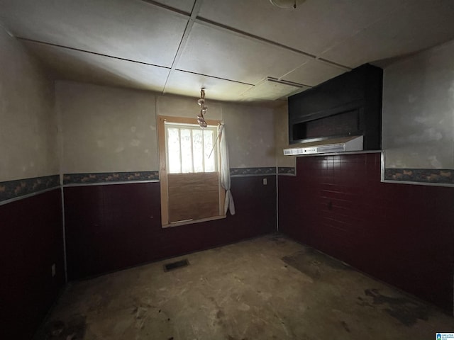 interior space featuring visible vents, wainscoting, and unfinished concrete floors