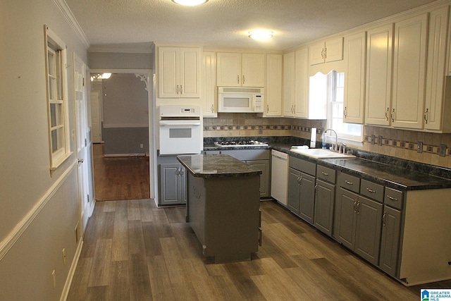 kitchen featuring a textured ceiling, white appliances, a kitchen island, sink, and white cabinetry