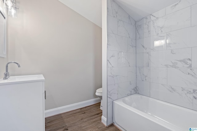 full bathroom featuring tiled shower / bath combo, vanity, vaulted ceiling, wood-type flooring, and toilet