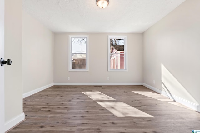 unfurnished room featuring wood-type flooring and a textured ceiling