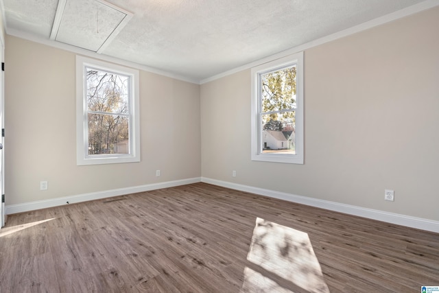 spare room featuring hardwood / wood-style floors, ornamental molding, and a textured ceiling