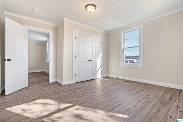 unfurnished bedroom with a textured ceiling, light hardwood / wood-style floors, a closet, and ornamental molding