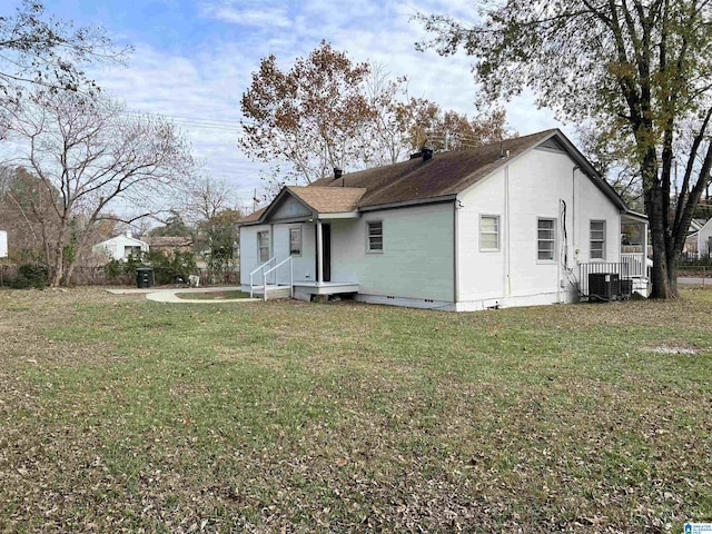 back of property with a yard and central AC