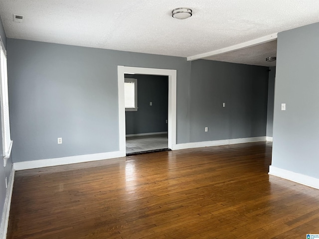 unfurnished room featuring dark wood-type flooring and a textured ceiling